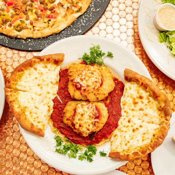 Chicken parmesan with spaghetti and two slices of cheesy garlic bread, alongside a pizza.